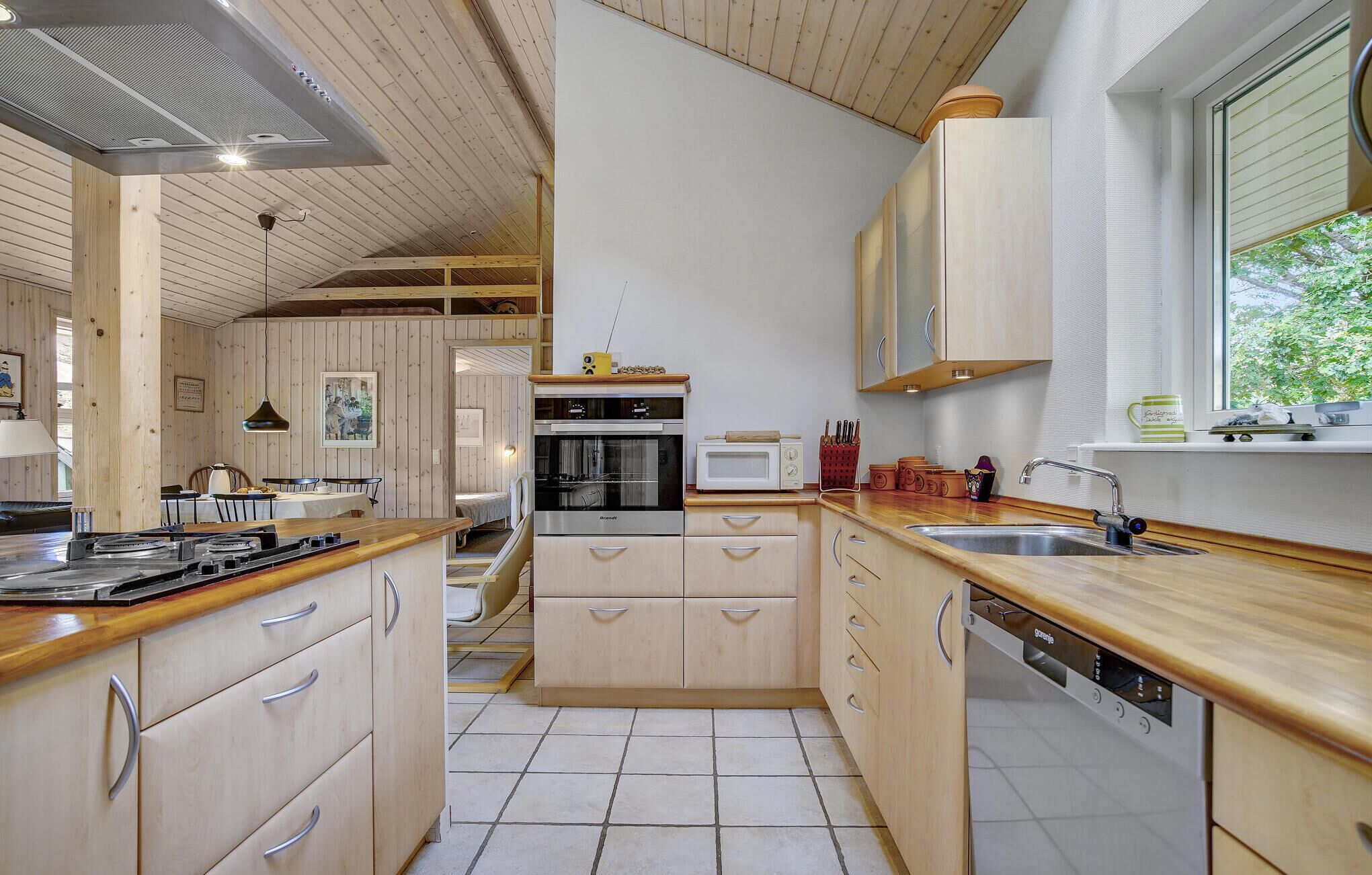 A modern kitchen with wooden cabinets, a built-in oven, microwave, and dishwasher.