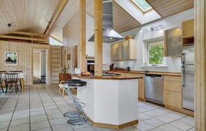 Een moderne keuken met houten details, een centraal eiland, roestvrijstalen apparatuur en een dakraam.