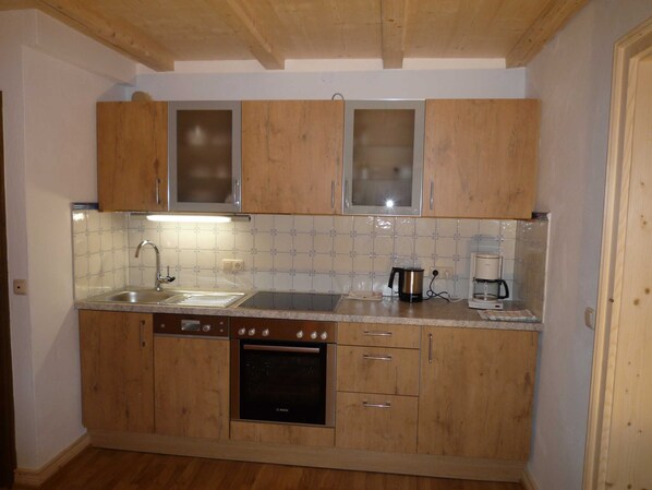 A kitchen with wooden cabinets, a Bosch oven, a sink, and a coffee maker.