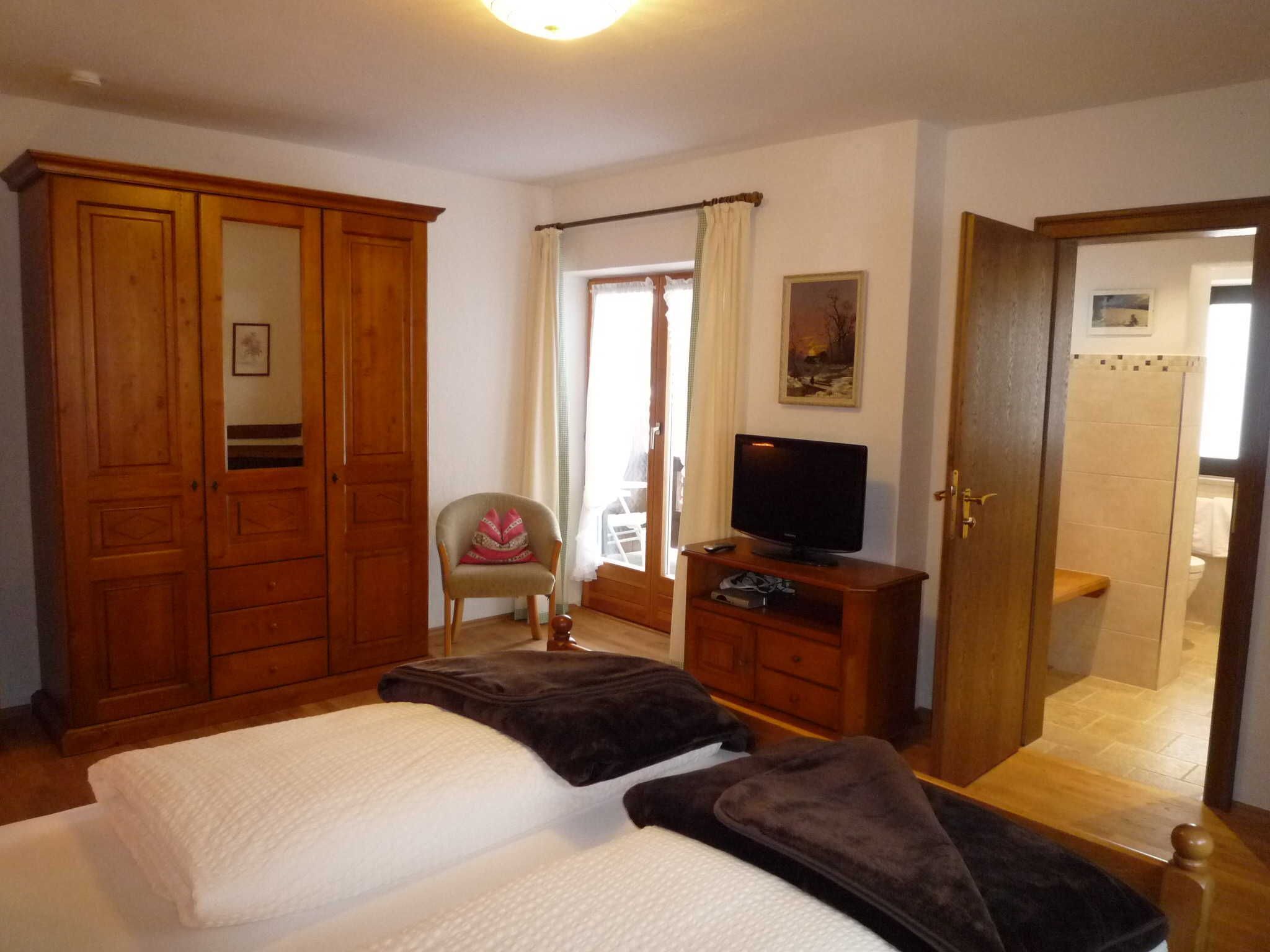 Une chambre à coucher avec un lit, une chaise, un téléviseur et une armoire.