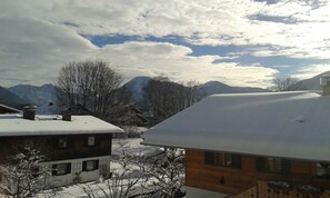 A snowy mountain village with traditional houses and a mountain in the background. - Apartment, 1st floor, No. 2, south and large west-facing balcony - Gästehaus Johanna (Bad Wiessee)