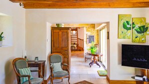A spacious living room with wooden furniture, a stone wall, and artwork on the wall. - Cozy home in La Cassagne (La Cassagne)