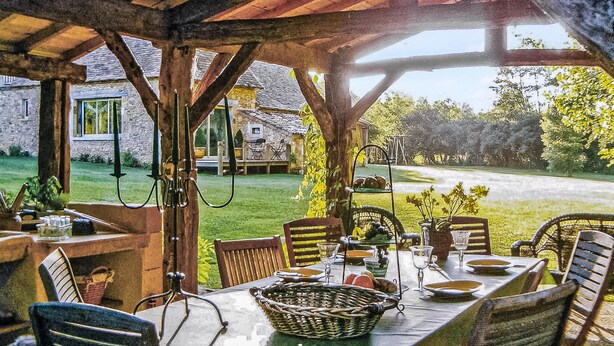 An outdoor dining area with a table set for four, surrounded by wicker chairs, under a wooden pergola. - Cozy home in La Cassagne (La Cassagne)