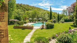 A pool surrounded by a well-maintained garden with a stone pathway leading to the pool, a gazebo, and lounge chairs. - Cozy home in La Cassagne (La Cassagne)