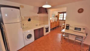 Une cuisine compacte équipée d’un lave-linge, d’une cuisinière, d’un four à micro-ondes et d’un coin repas avec deux chaises.