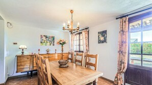 Une salle à manger avec une table en bois, des chaises, un lustre et des œuvres d’art accrochées aux murs.