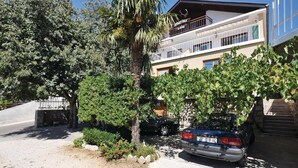 Ein Gebäude mit Balkon und einem geparkten Auto davor.