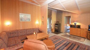 A cozy living room with a wooden interior, a sofa, a coffee table, and a fireplace. - Beautiful home in Væggerløse with sauna (Væggerløse)