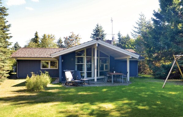 Une maison de plain-pied avec un patio couvert, un petit abri de jardin et une pelouse.