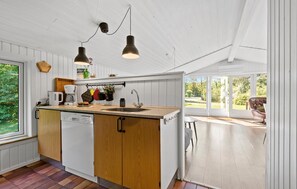 A modern kitchen with wooden cabinets, a built-in dishwasher, a large window, and a view of the outdoors. - Nice home in Oksbøl with sauna (Oksbøl)