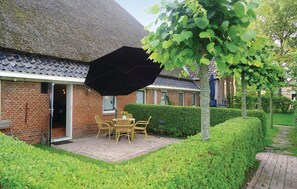 Relax in a charming outdoor seating area with a table and two chairs, shaded by a large umbrella.