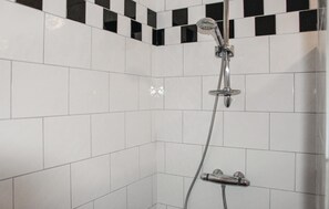 Enjoy a refreshing shower experience with a chrome showerhead and handheld shower attachment in this stylish bathroom.