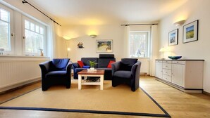 Una sala de estar con dos sillones, un sofá, una mesa de centro y un aparador.