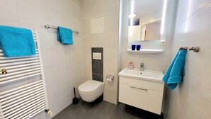 Un baño moderno con inodoro, lavamanos y toallero.