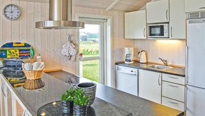 A modern kitchen with white cabinets, a stainless steel range hood, a microwave, and a dishwasher. There is a window with a view of a green landscape. - Awesome home in Haderslev with WiFi (Haderslev)