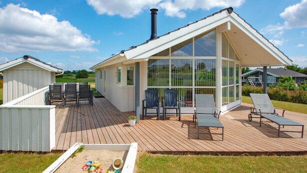 A modern house with a large glass extension, a deck with outdoor furniture, and a small play area with toys. - Awesome home in Haderslev with WiFi (Haderslev)
