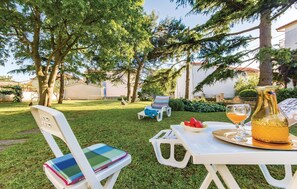 Ein Sitzbereich im Freien mit Tisch, Stühlen und einem Getränk.