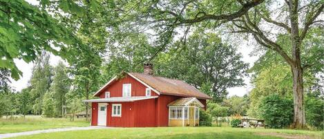 A red barn with a white door and windows, surrounded by lush greenery and trees.