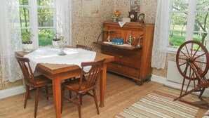 A dining room with a wooden table, chairs, a wooden cabinet, and a spinning wheel. - 1 bedroom amazing home in Brålanda (Brålanda)