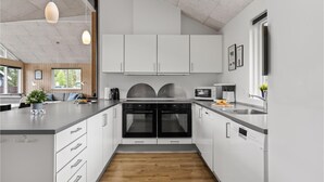 A modern kitchen with white cabinetry, a central island, and a built-in oven. - Beautiful home in ålbæk with kitchen (Ålbæk)