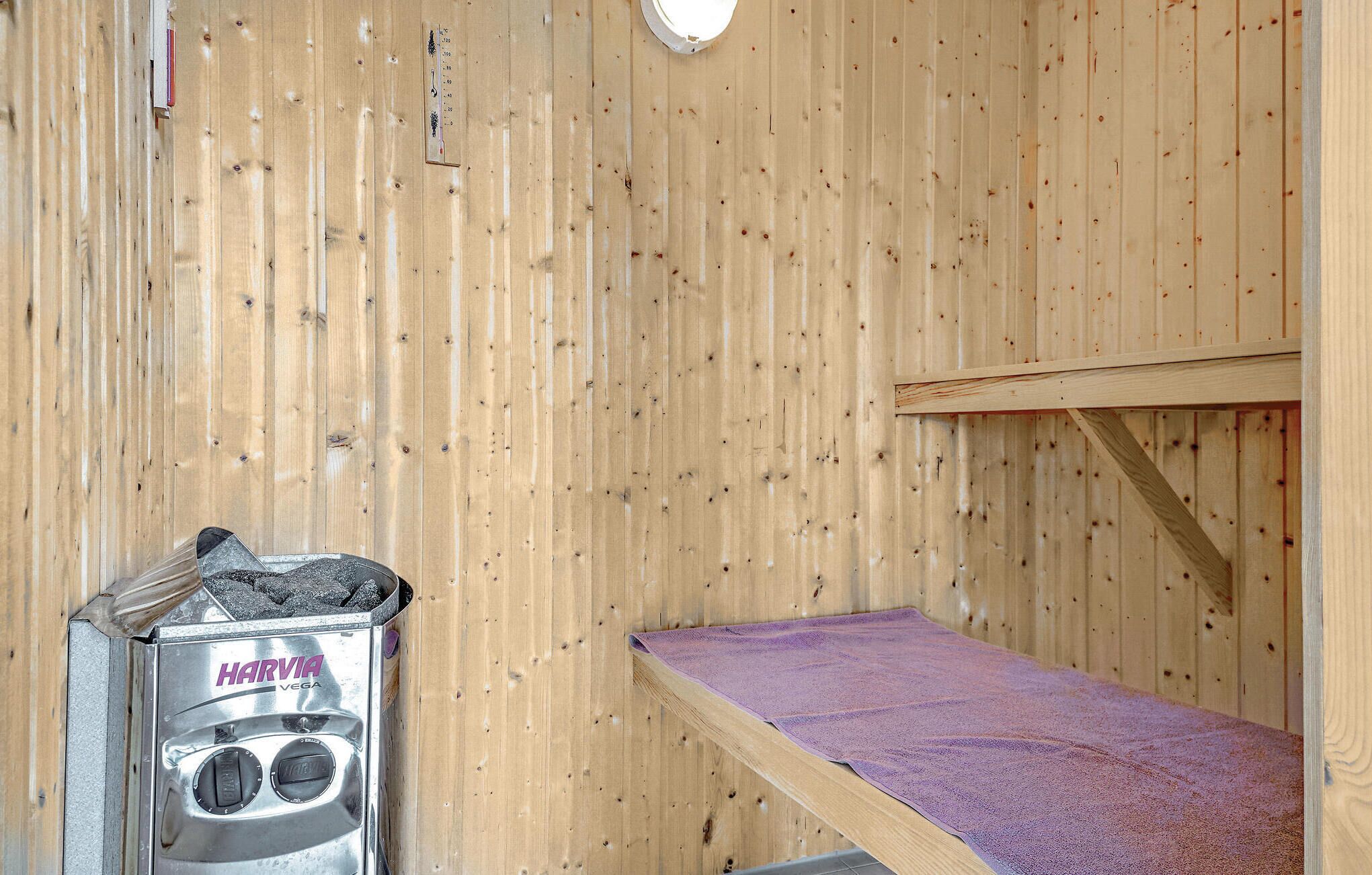 Un sauna con pared de madera, un banco y un calentador de sauna marcado 'HARVIA VEGA'.
