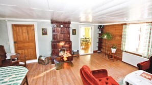 A cozy living room with a wooden floor, a fireplace, a dining area, and a red armchair. - 3 bedroom amazing home in Svenljunga (Svenljunga)