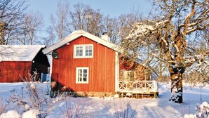 A red wooden house with a white door and windows, surrounded by snow-covered ground and trees. - 3 bedroom amazing home in Svenljunga (Svenljunga)
