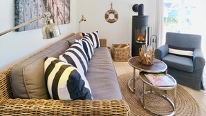 Ein gemütliches Wohnzimmer mit einer Couch, einem Sessel, einem Kamin und einem Korbwannenmöbel.