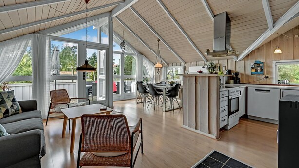 A spacious loft with a high ceiling, large windows, a dining area, and a kitchen.