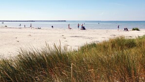 A beach with people sunbathing and swimming.