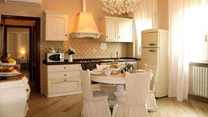 A kitchen with white cabinets, a chandelier, a dining table with chairs, and a refrigerator. - Holiday apartment mit Pool (Montecarlo Lucca)
