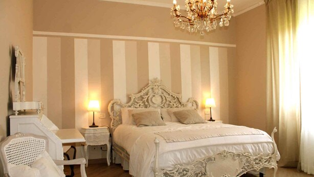 A classic bedroom with a four-poster bed, two bedside tables, a chair, and a chandelier. - Holiday apartment mit Pool (Montecarlo Lucca)