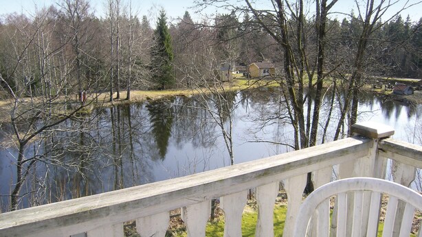 En utsikt över sjön med en träveranda och en stol.
