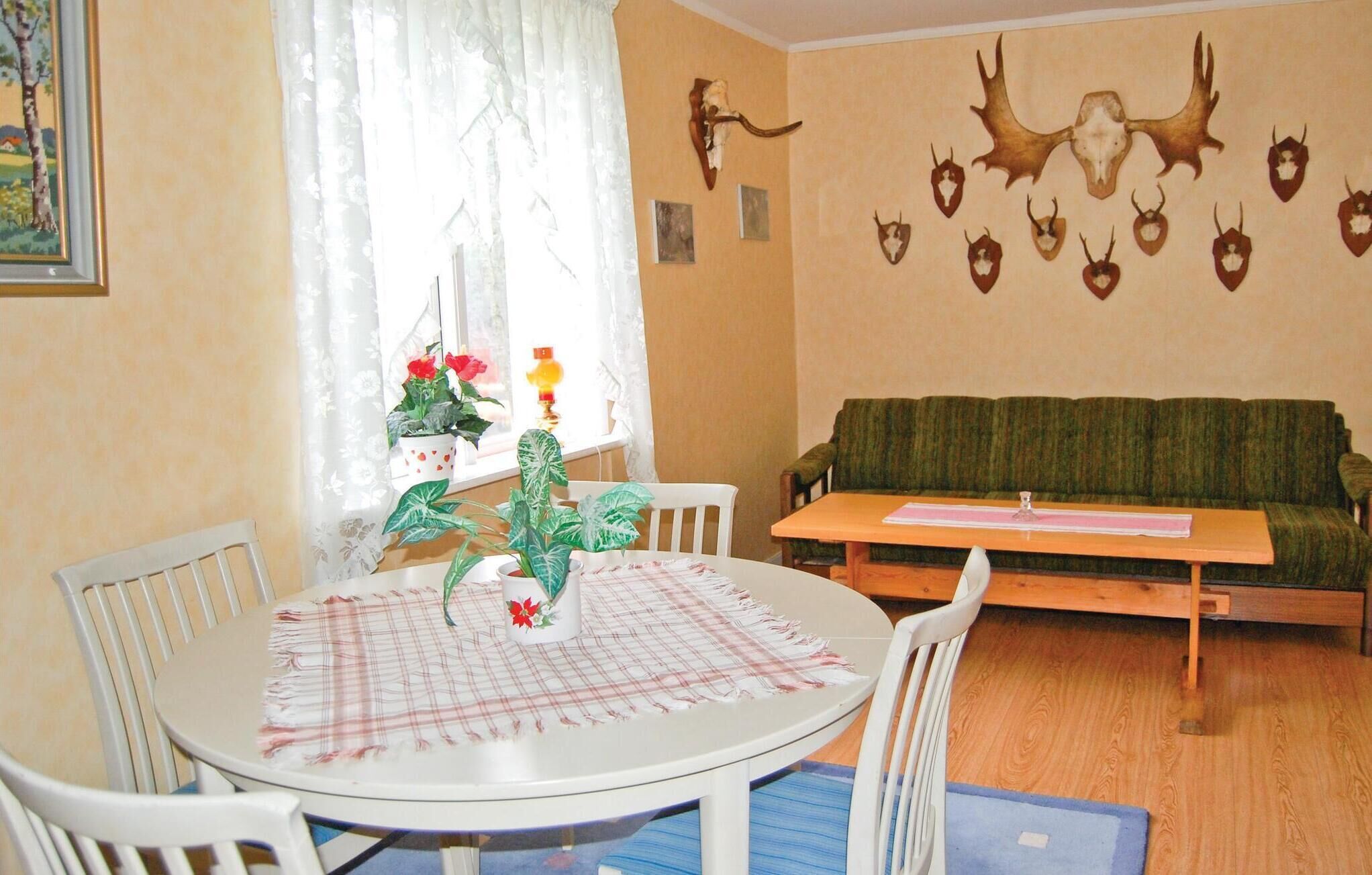 A dining area with a round table, chairs, and a green sofa.