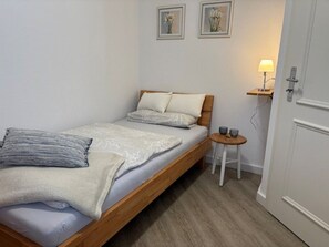 A bedroom with a wooden bed, a bedside table with a lamp, and two framed pictures on the wall. - (91) 3-room apartment south-facing balcony - apartment house Atlantic (Kühlungsborn)