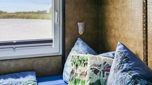 Une pièce dotée d’une grande fenêtre, d’un mur en bois et d’un lit avec une literie bleue et des coussins décoratifs.