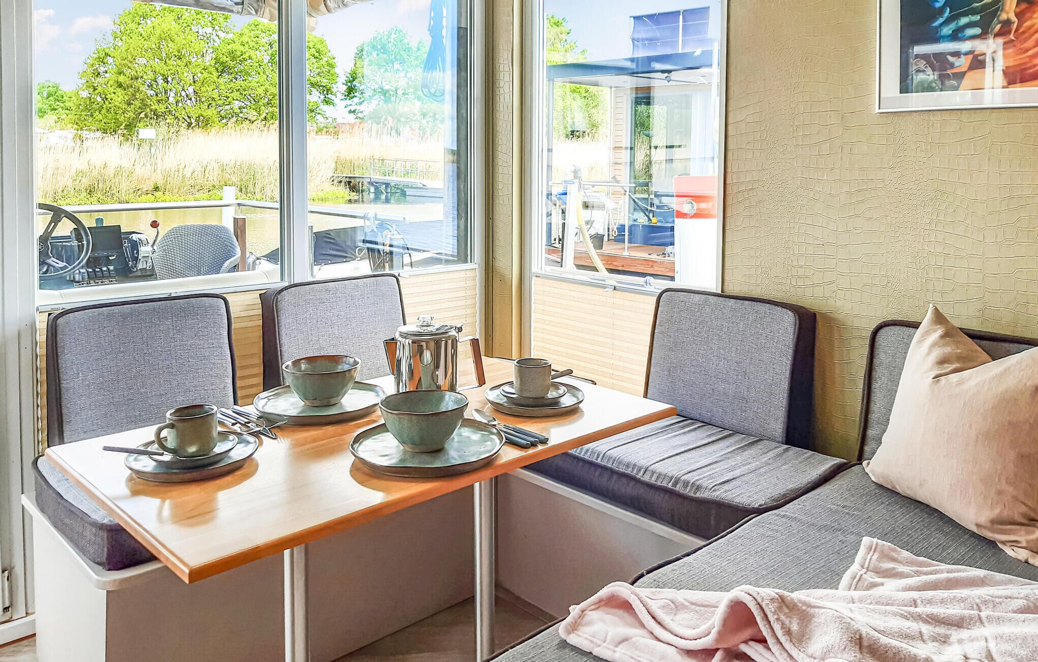 Een zithoek met een tafel gedekt voor twee personen, een raam met uitzicht op een park, en een bakstenen muur.