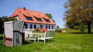 Een huis met een rood dak, witte muren en een tuin met een tafel en stoelen.