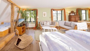 Een knus ingerichte kamer met een bed, een slaapbank, een stoel, een televisie en een houten kast.