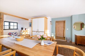 A dining area with a wooden table, chairs, a vase of flowers, and a white cabinet.