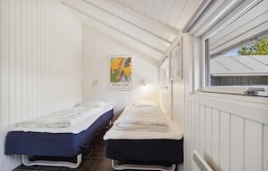 Cozy single-room accommodation with two single beds, a skylight, and a window offering a view.