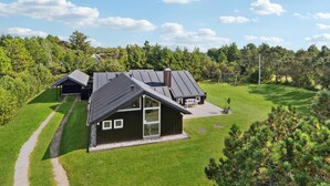 Une maison moderne avec un toit en pente, une grande baie vitrée et une pelouse bien entretenue.