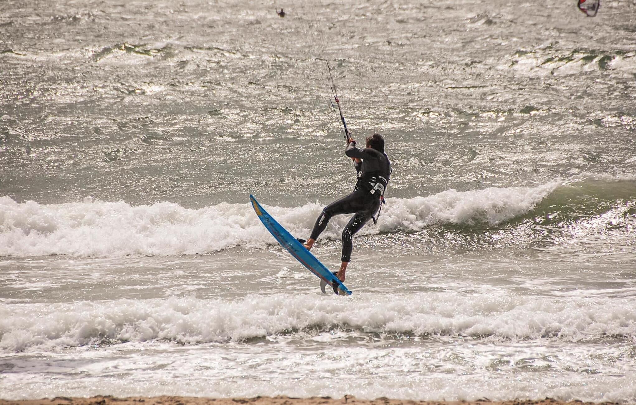 Une personne pratiquant la planche à voile sur une planche bleue, au large.