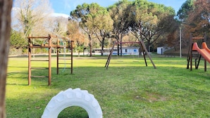 Un parque infantil con un columpio de neumático, estructuras de madera para escalar y un tobogán.