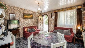 Una sala de estar acogedora con pared de piedra, chimenea, televisor y mesa de comedor con sillas.