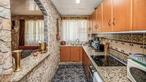 Una cocina con paredes de piedra, armarios de madera y un salpicadero de azulejos.