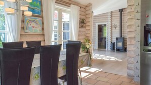 Un intérieur chaleureux avec un coin repas, des murs en bois, une cheminée et des œuvres d’art accrochées aux murs.