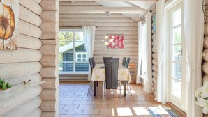 L’intérieur d’une cabane en rondins comprend un coin repas, des murs en bois et de grandes fenêtres.