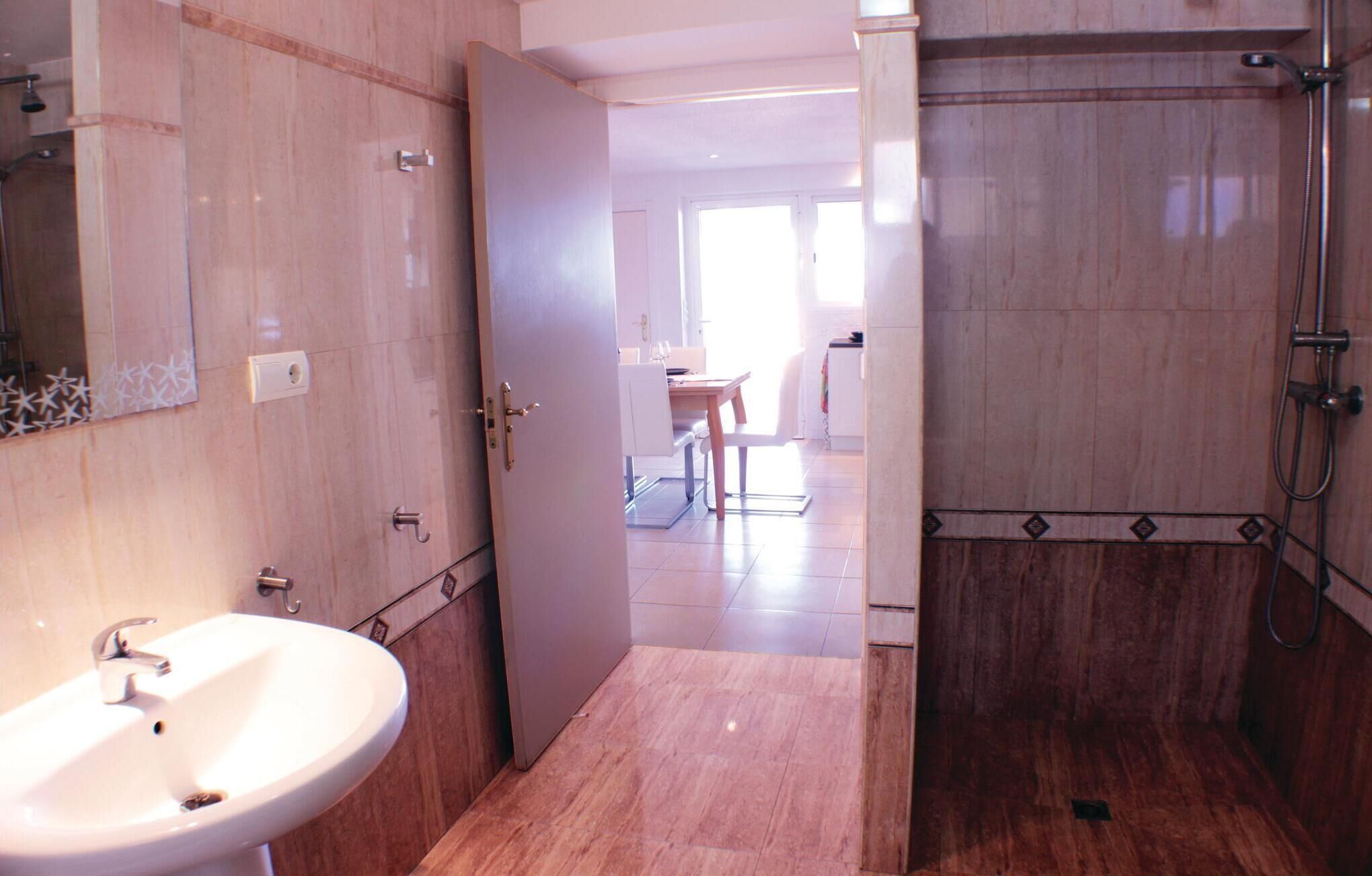 Een badkamer met een wastafel, spiegel en douche.