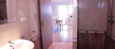 A bathroom with a sink, mirror, and shower.